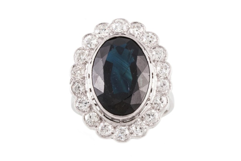 A SAPPHIRE AND DIAMOND OVAL CLUSTER RING, with one oval cut ...