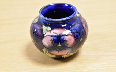 A William Moorcroft squat vase, in the Pansy pattern against a blue ground, measuring 6.5cm tall