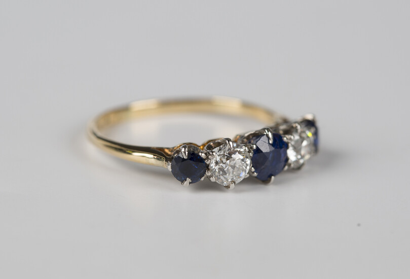 A gold and platinum, sapphire and diamond five stone ring, claw set with three cushion cut sapphires