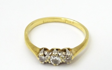 A gold ring set with a trio of diamonds in a platinum settin...