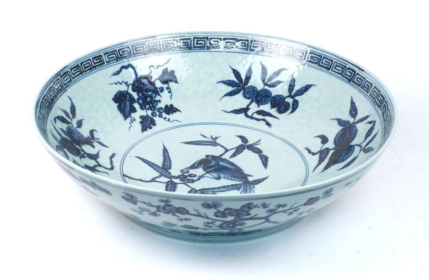 A large Chinese blue and white bowl, 20th century, decorated to interior with a bird eating berries off a branch to centre within panel of fruit on branches within a Greek key border, the exterior decorated with trees, 15.4cm high, 55cm diameter
