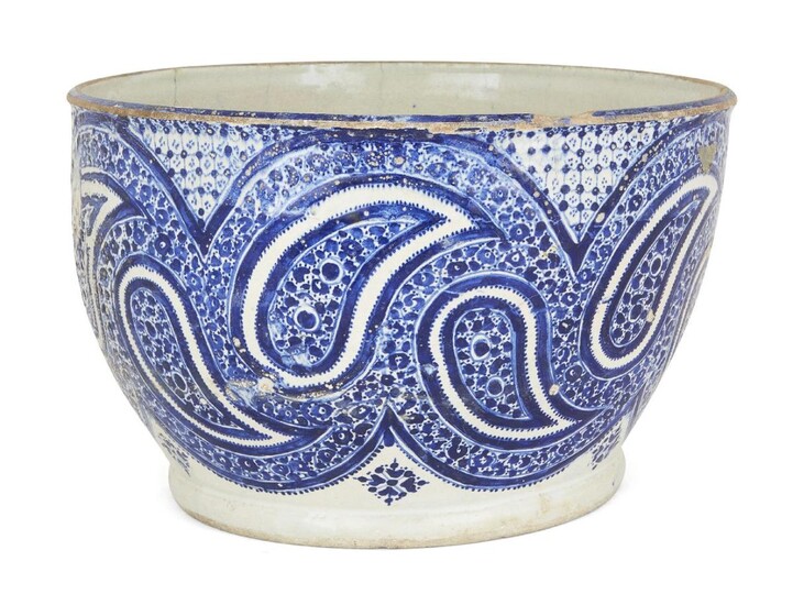 A large Qajar blue and white pottery bowl, Iran, late 19th/early 20th century, of deep rounded form, deocrated to body with design of swirling boteh motifs, 21cm. high x 32cm. diam.