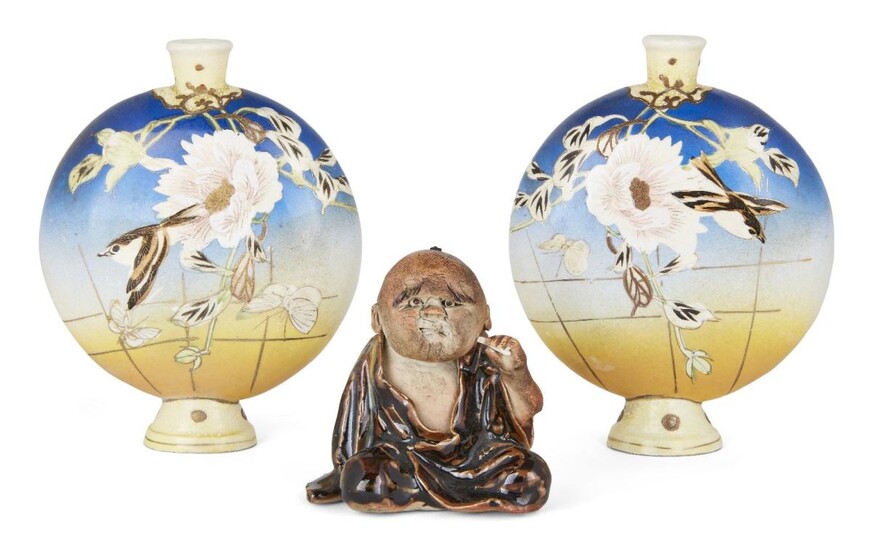 A pair of Satsuma moonflasks and a seated figure, late 19th century, moonflasks decorated with birds and flowers against a European-taste colour gradient; seated ceramic figure with richly glazed robe and characterful expression, each vase 17cm...
