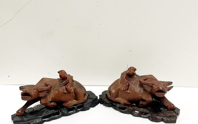 A pair of mid 20thC Chinese carved hardwood figures of water buffalo on carved wooden stands W. 21cm. (A/F)
