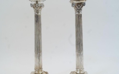 A pair of white metal Corinthian column candlesticks, the detachable sconces with gadrooned border, on filled stepped square bases with foliate decoration, the sconces engraved H J & Co, approx. 34cm high (2)
