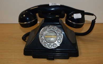A vintage bakelite rotary dial telephone in black, measuring 15cm tall