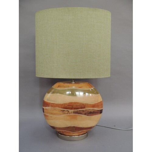 A wood effect strata table lamp of flattened moon shape on a...