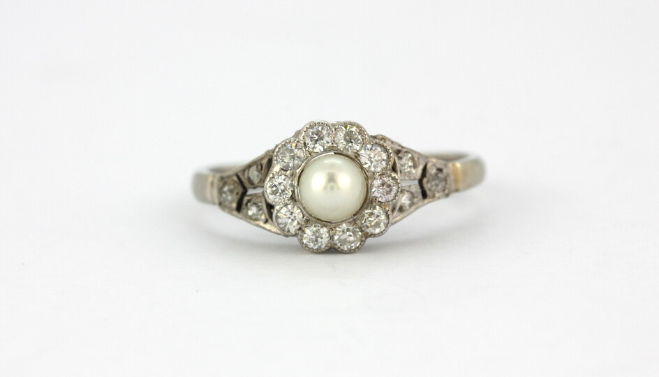 An early 20th century white metal (tested high carat gold) pearl and diamond set ring, (N.5).