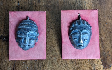 Deux petits masques africains en bronze. H. 8,5 cm.