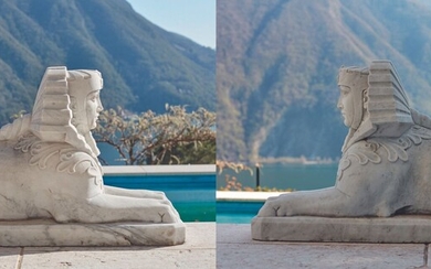 *Paire d'importants sphinx en marbre blanc sculpté, figurés coiffés d'un Némès. Les pattes antérieures étendues,...