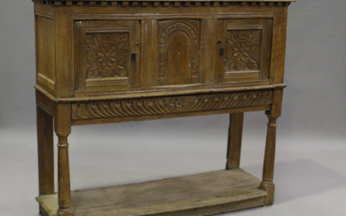 A 17th century oak side cupboard with carved decoration, fitted with two panel doors, on turned supp