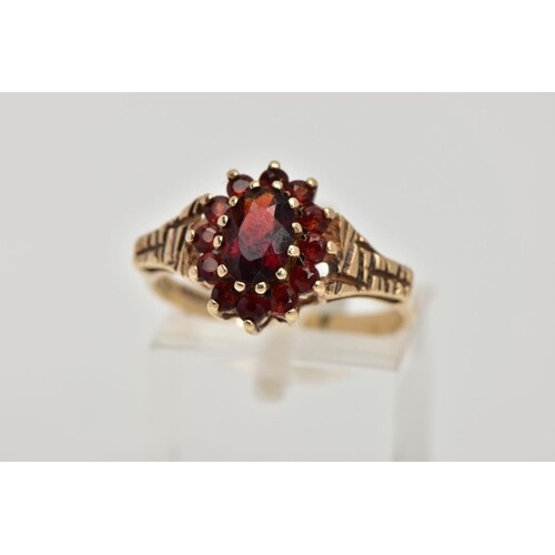 A 9CT GOLD GARNET DRESS RING, slightly raised cluster of an ...
