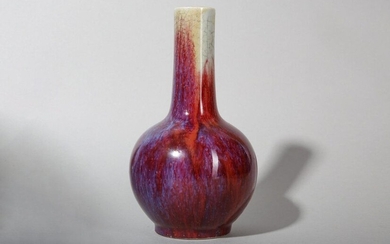 A CHINESE FLAMBÉ-GLAZED BOTTLE VASE. The globular body rising to a slightly tapering cylindrical neck, covered overall in a rich dark red glaze suffused with purple-blue streaks thinning to a buff tone at the rim, 19.5cm H. 窯變釉天球瓶