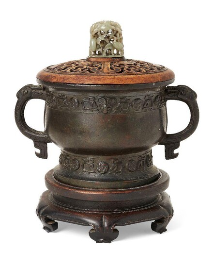 A Chinese archaistic bronze censer, gui, Ming dynasty, cast with a band of mythical animal-heads amongst kui dragons and raised roundels, applied with a pair of C-shaped zoomorphic handles, all resting on a similarly decorated foot, 26 cm wide...