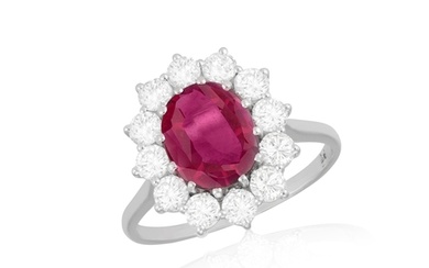 A RUBY AND DIAMOND CLUSTER RING The oval-shaped ruby within...