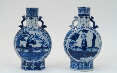 A pair of Chinese blue and white porcelain moon flasks, 19th century, each with twin ruyi sceptre handles and decorated to the body with figures in domestic settings, apocryphal Kang-xi mark to the underside, each 21cm high (2)