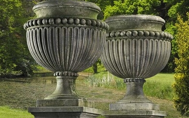 A pair of large and impressive Italian carved limestone garden urns on plinths in Impero taste
