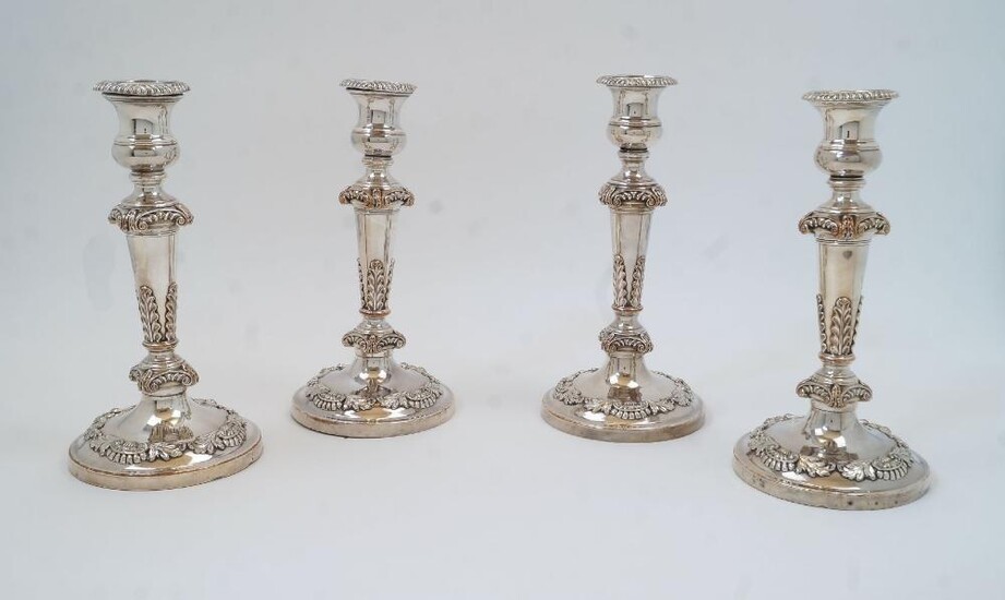 A set of four silver plated candlesticks, with urn sconces above foliate scrolling and tapering support with acanthus leaves, on circular base with foliate decoration, 23cm high