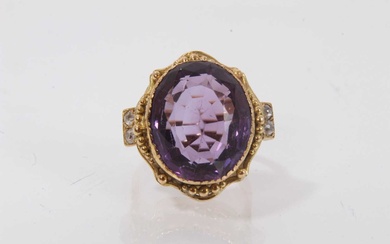 Amethyst and diamond ring with a large oval mixed cut amethyst in gold setting, diamond set shoulders on gold shank