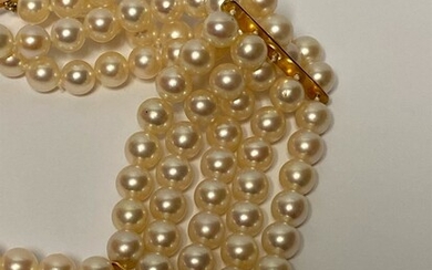 BRACELET composé de quatre rangs de perles de culture blanches, alternées de barettes en or...