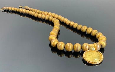 Collier en or jaune formé de boules d'or striées, en chute, retenant un pendentif orné d'une pièce byzantine en or.