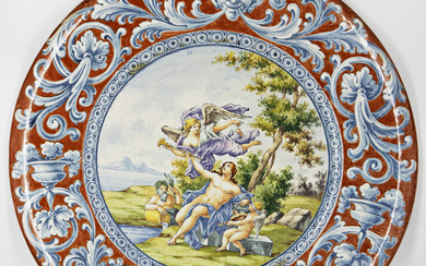 Grande piatto da parete in maiolica dipinta in policromia nel cavetto con scena allegorica e tesa a mascheroni entro volute…