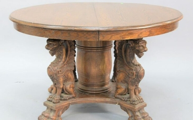 Round oak dining table having pedestal base with winged