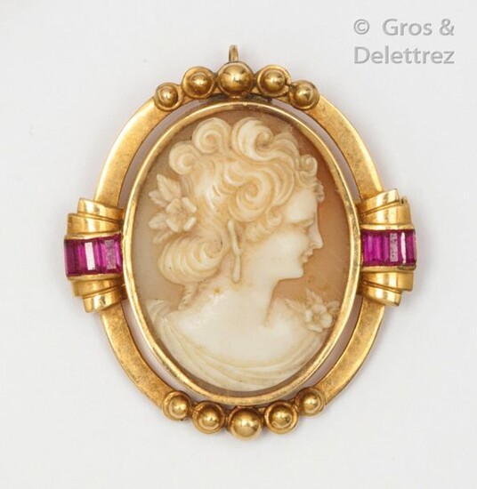 Yellow gold brooch, adorned with a shell cameo representing the profile of a woman with calibrated red stones. Dimensions: 3.5 x 3.8cm. Raw weight: 12.4g.