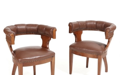 A pair of circa 1910 oak library chairs, upholstered with brown leather fitted with brass nails.