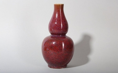 A CHINESE FLAMBÉ GLAZED DOUBLE GOURD VASE. The globular lower bulb surmounted by a smaller ovoid-form upper bulb rising to a slender neck, covered with a mottled cranberry, purple and brick red glaze thinning to a mushroom tone at the rim, 23cm H. 窯變釉葫蘆瓶