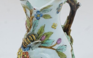 A Chelsea style goat and bee jug, probably 19th century, of typical form with applied foliage and bee to body and naturalistically modelled tree branch handle, painted with butterflies and flowers, unmarked base, 11cm high (AF)