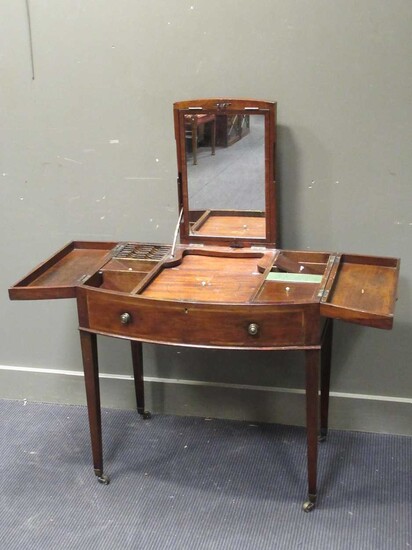 A George III mahogany bow front dressing table, the adjustable top revealing a mirror, the side