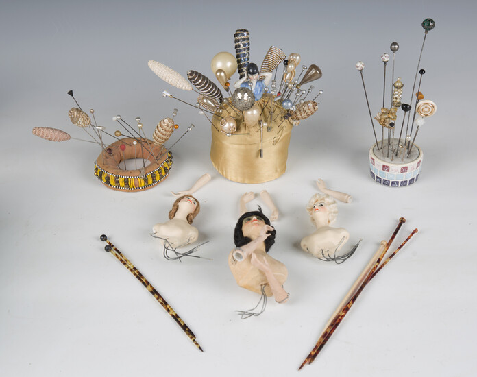 A collection of mainly early/mid-20th century hatpins, pin cushions and four doll's head handle