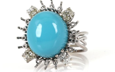 A diamond ring set with a cabochon blue stone encircled by eight...
