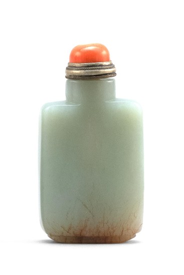 CHINESE CELADON AND RUSSET JADE SNUFF BOTTLE In rectangular form, with russet inclusions at foot. Height 2.6". Coral stopper.