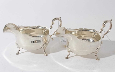 Pair of Edwardian silver sauce boats of conventional form with scroll handles, each raised on three hoof feet, (London 1901) makers mark rubbed, all at approximately 10.5oz, 16cm from handle to spout.