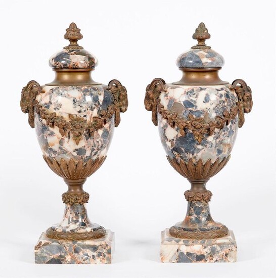 Pair of Louis XVI style bronze and marble CASSOLETTES. The base encircled by a frieze of laurel, the simulated holds in the shape of rams joined by garlands of flowers. The solid lid surmounted by a pomegranate. France, late 19th century Height. 44 cm.