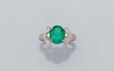 Ring in white gold, 750 MM, set with an oval emerald weighing 2.46 carats between two brilliants set in two underlined patterns of baguette-cut diamonds, size: 54, weight: 3.65gr. rough.