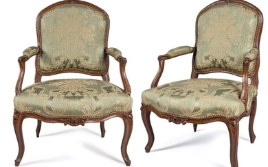 TWO QUEEN LOUIS XV FALLS in moulded and sculpted beech wood, the violin-shaped backrests, decorated with the cushioning of flowers surrounded by a garland of plants or a bouquet, the armrests with cuffs ending in windings, the consoles slightly moved...