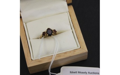 A 9ct gold three stone garnet dress-ring.