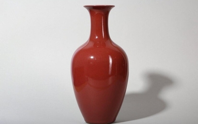 A CHINESE COPPER RED GLAZED VASE. With an elongated body and wide shoulders high sides and a wide shoulders, covered in an even deep red glaze, the interior and base glazed white, 27.5cm H. 紅釉撇口樽