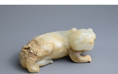 A CHINESE PALE CELADON AND RUSSET JADE CARVING OF A LION, MI...
