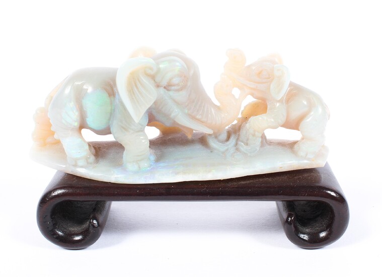 A Oriental carved opal model of an elephant and calf, mounted on a hardwood plinth stand.