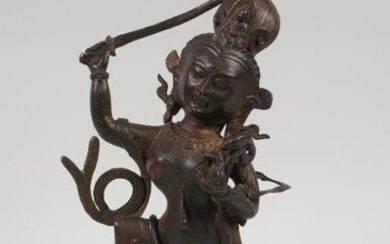 A Tibetan bronze figure of a deity standing over...