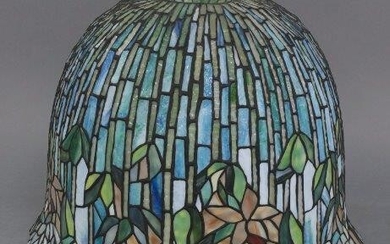 A Tiffany style lamp shade, produced by La Galerie du Vitrail, Chatres, France, c.1999, of domed form, with flowering lotus pattern in leaded and stained glass, 38cm high, 50.5cm diameter