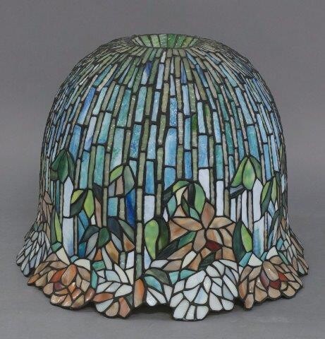 A Tiffany style lamp shade, produced by La Galerie du Vitrail, Chatres, France, c.1999, of domed form, with flowering lotus pattern in leaded and stained glass, 38cm high, 50.5cm diameter
