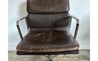 A Vitra Eames soft pad chair with brown leather and chrome o...