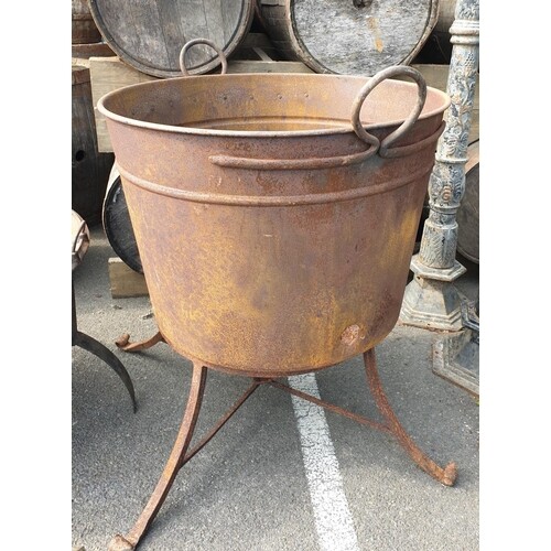 A large Metal Cauldron on a cast iron base. Diam. 86 x H 100...