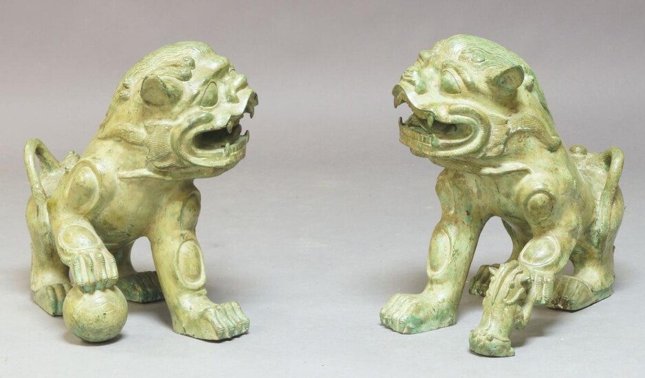 A pair of Chinese bronze temple lions, 20th century, one cast with a smaller temple lion by its side, the other with a ball beneath its foot, 44cm long (2)