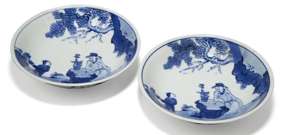 A pair of Chinese porcelain blue and white saucer dishes, Republic period, each painted with a scholar seated at a rock taking tea with an attendant, 17cm diameter